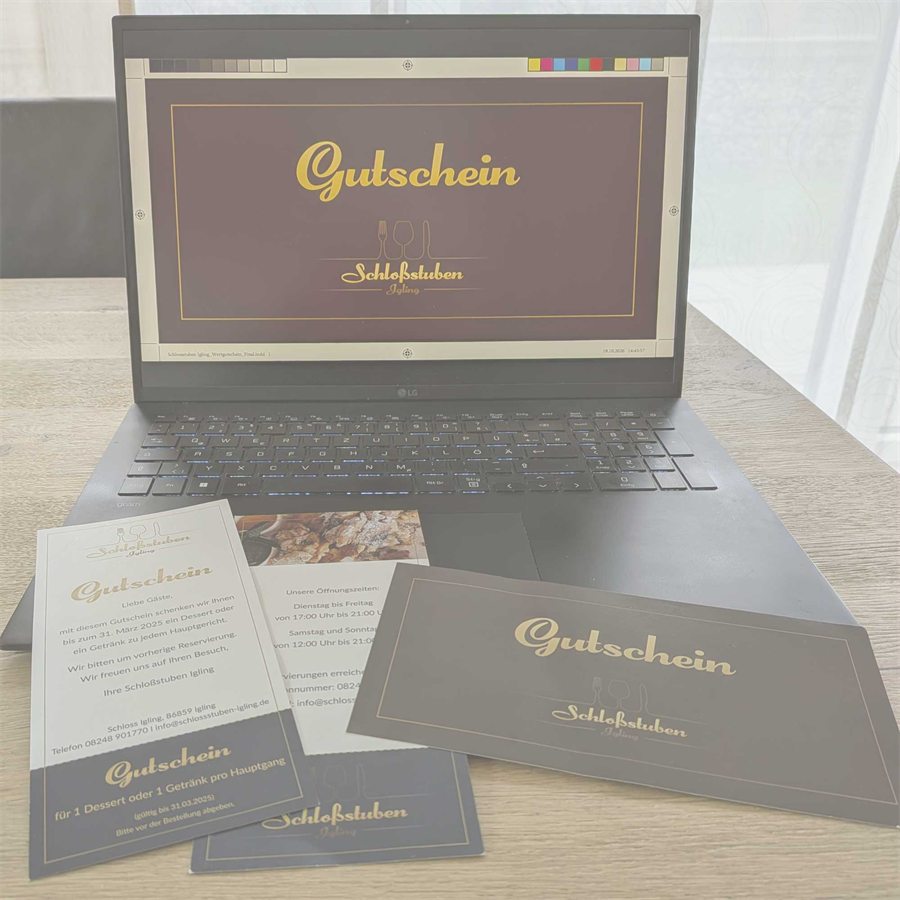 Gedruckte Gutscheine und ein Flyer der Schloßstuben Igling vor einem Laptop mit dem Gutschein-Entwurf